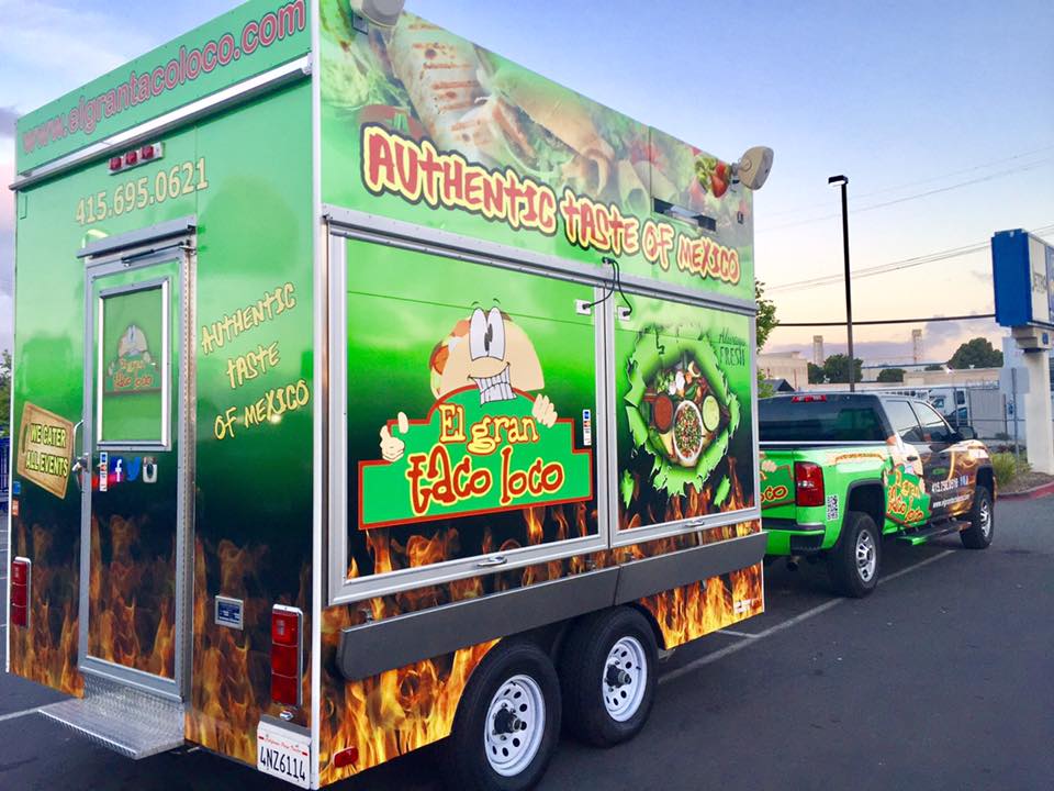 El Gran Taco Loco's green taco truck with its logo and painted flames.