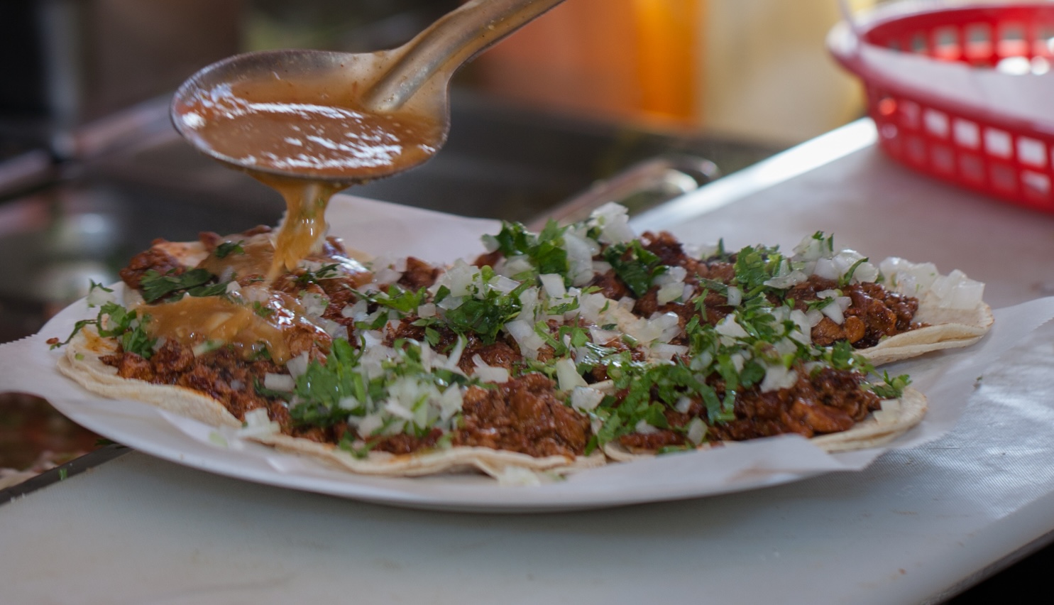 Salsa being poured over fresh street tacos.